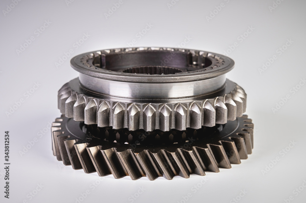 New parts on a gray background. Gears of gear shifting torque transmission. Conceptually mechanical background. Shiny gear box gear teeth New parts on a gray background. Gears of gear shifting torque transmission. Conceptually mechanical background. Shiny gear box gear teeth