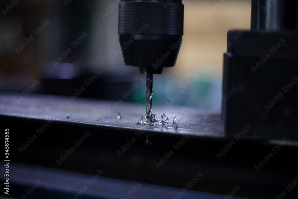 A modern drill for creating holes in metal. Work as a drill in the workshop. Replacing the drill after use. Preparing for work. Background is my hobby. Drill holes in a metal beam.