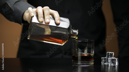 Pouring whiskey, cognac into glass. Bartender pours alcohol drink. Silhouette