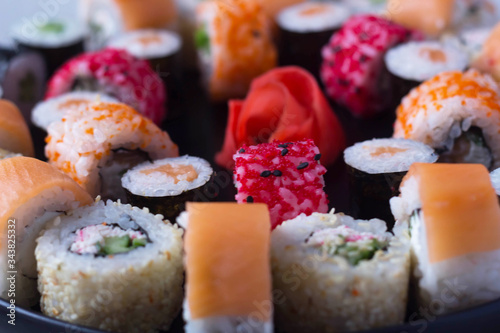 sushi and rolls lie on a flat plate, next to chopsticks, ginger and wasabi. sushi and roll delivery, contactless delivery during the coronavirus epidemic