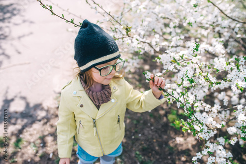 Little girl in sunglasses having fun in apple spring garden. Top view