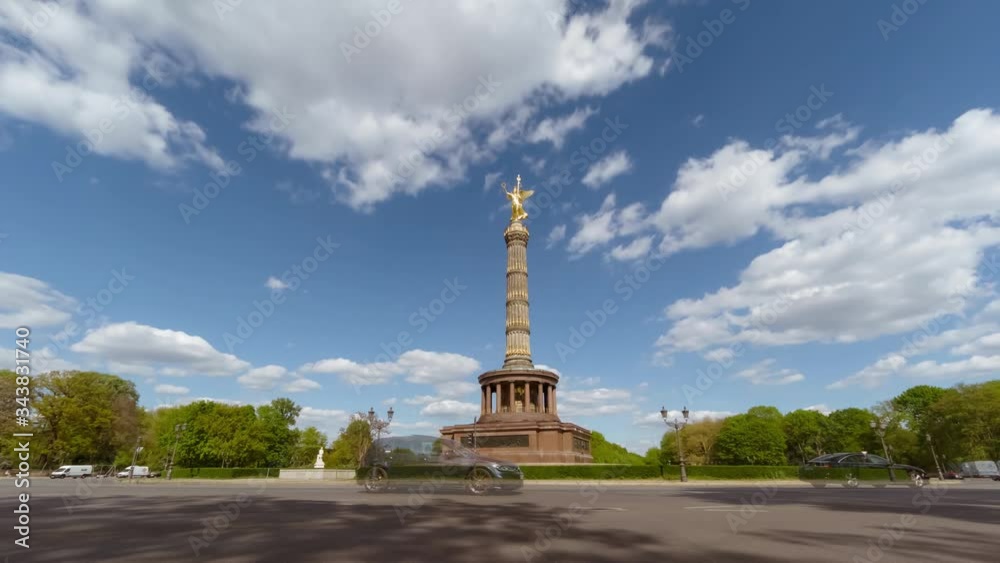 Timelapse of the famous Victory Column (Siegessäule) against blue sky in sunny day with traffic car, Victoria statue with golden silhouette Timelapse of the famous Victory Column (Siegessäule) against blue sky in sunny day with traffic car, Victoria statue with golden silhouette