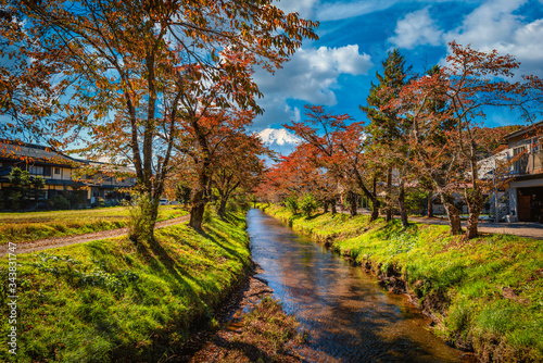 Landscape image of Mt. Fuji over canal with autumn foliage at daytime in Minamitsuru District, Yamanashi Prefecture, Japan.
