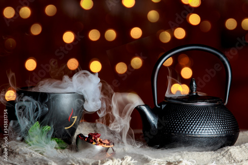 Smoking hot herbal tea in a black pot.  Bio tea with christmas background photo