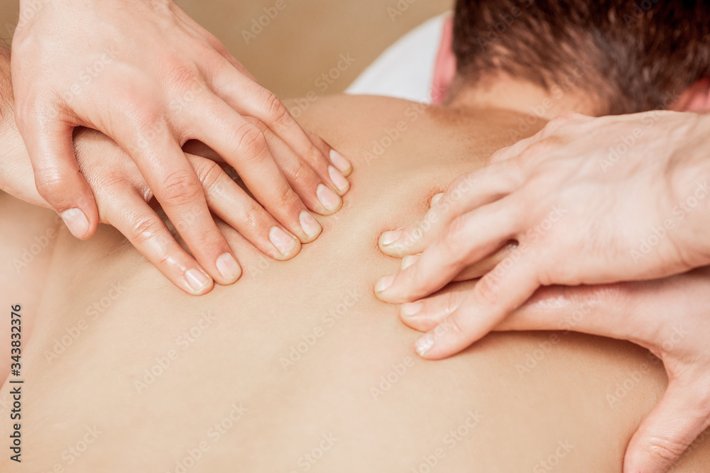 Close-up of massage therapists hands massaging man's back in spa. Close-up of massage therapists hands massaging man's back in spa.