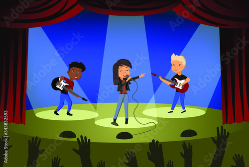 Children's rock band performs on stage. Two boys with guitars and a girl soloist. Vector illustration in flat style.