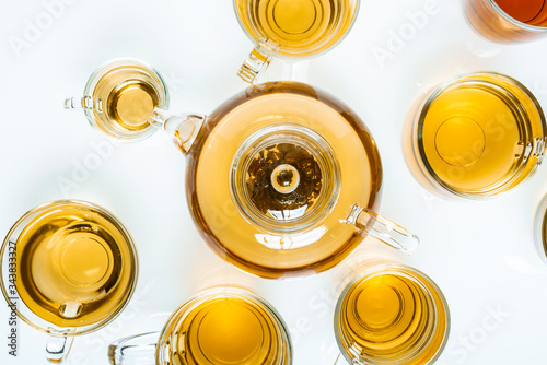 glass teapot and cups with hot tea on table, top view