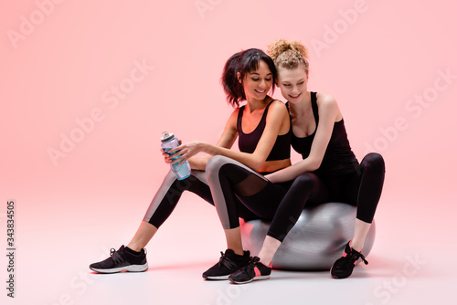 happy girl sitting on fitness mall with cheerful african american woman on pink © LIGHTFIELD STUDIOS