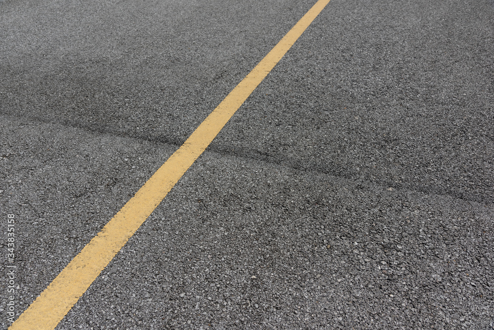 Fototapeta premium Yellow paint line on old asphalt road