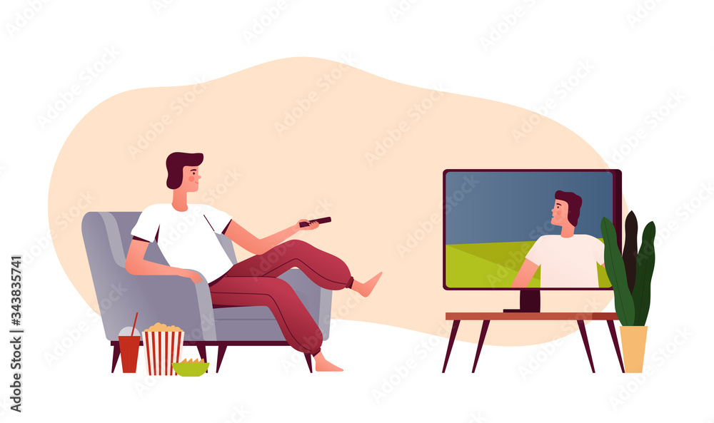 Young man sits in his house on an armchair with popcorn and watches TV. Home daily activities. People home entertainment Young man sits in his house on an armchair with popcorn and watches TV. Home daily activities. People home entertainment