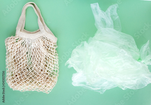 String reusable bag and a pile of plastic bags on green background, zero vaste concept. Top view