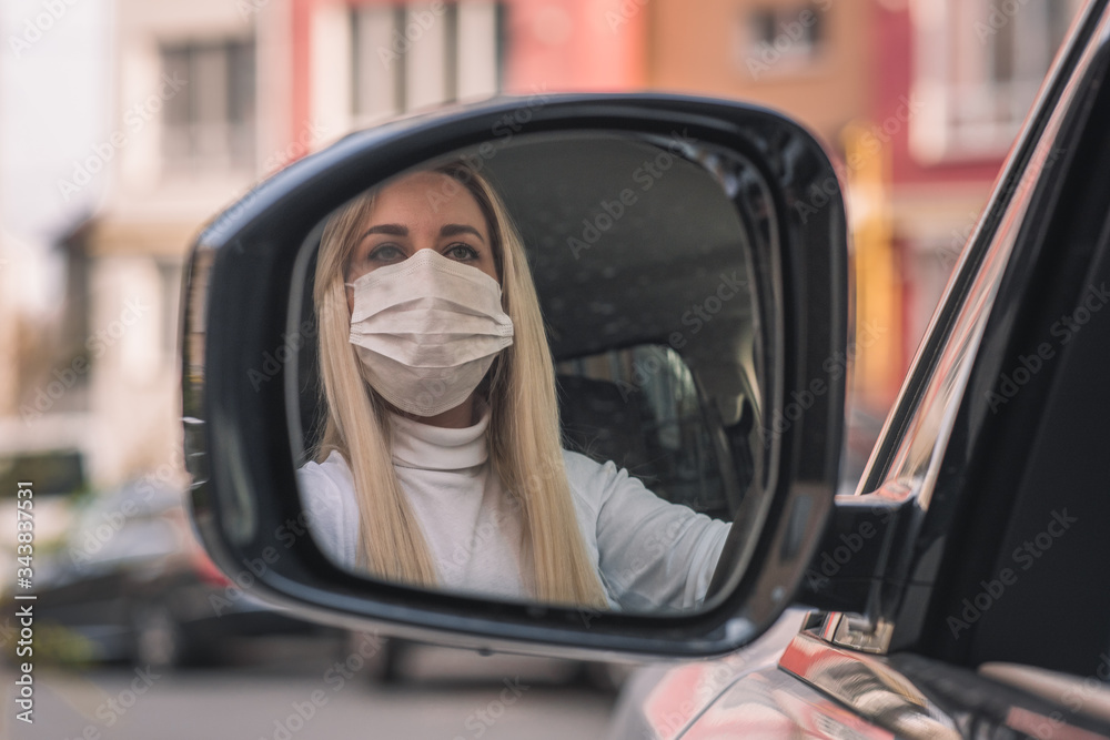 girl in a medical mask. beautiful blonde photo in a car mirror