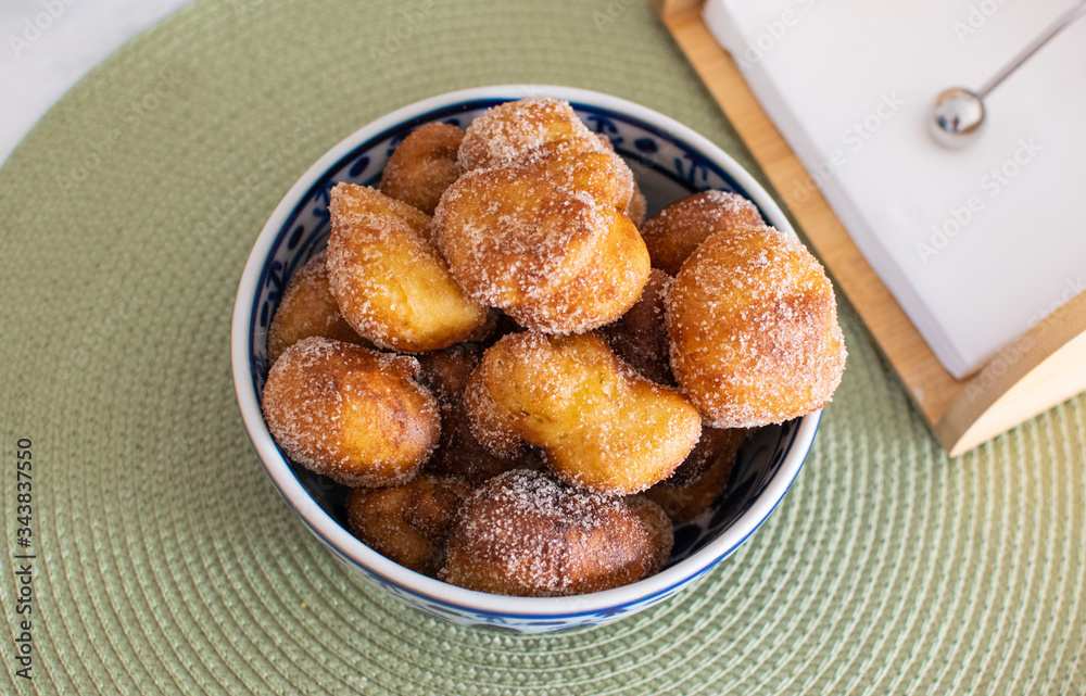 Traditional Brazilian mini fried cakes called bolinho de chuva in a bowl in a green breakfast background