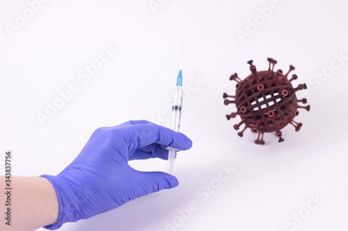 Pandemic covid19 concept.Hand in blue medical glove with syringe isolated and blurred 3d model of coronavirus on a white background. Symbol of cessation of illness, stopping the epidemic.copy space