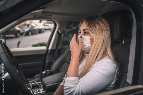 girl in a medical mask. beautiful blonde driving an expensive car. coronavirus, disease, infection, quarantine, medical mask, covid-19 © Evghenii Blanaru