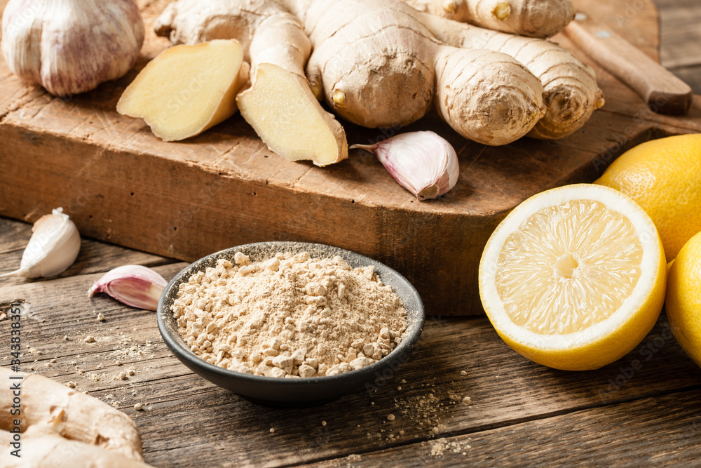 Ginger root, ginger powder, garlic and fresh lemons on wooden table Ginger root, ginger powder, garlic and fresh lemons on wooden table