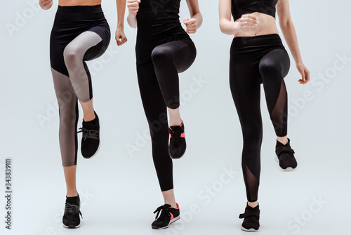 cropped view of multicultural women in sportswear training on white