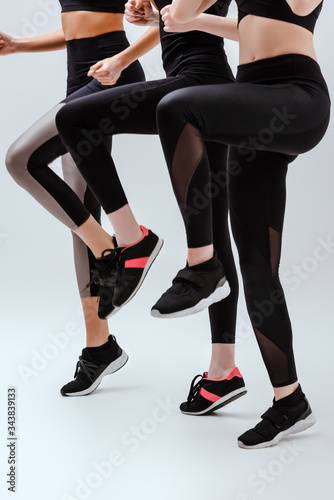 cropped view of multicultural women in sportswear exercising on white