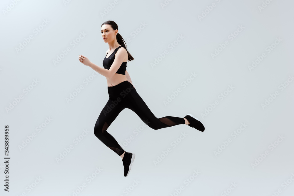 pretty woman in black sportswear jumping isolated on white