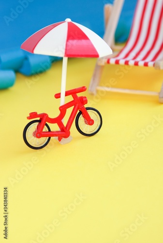 Red toy bicycle and beach umbrells with summer cocktail against sea. Summer rest. Vacations near sea