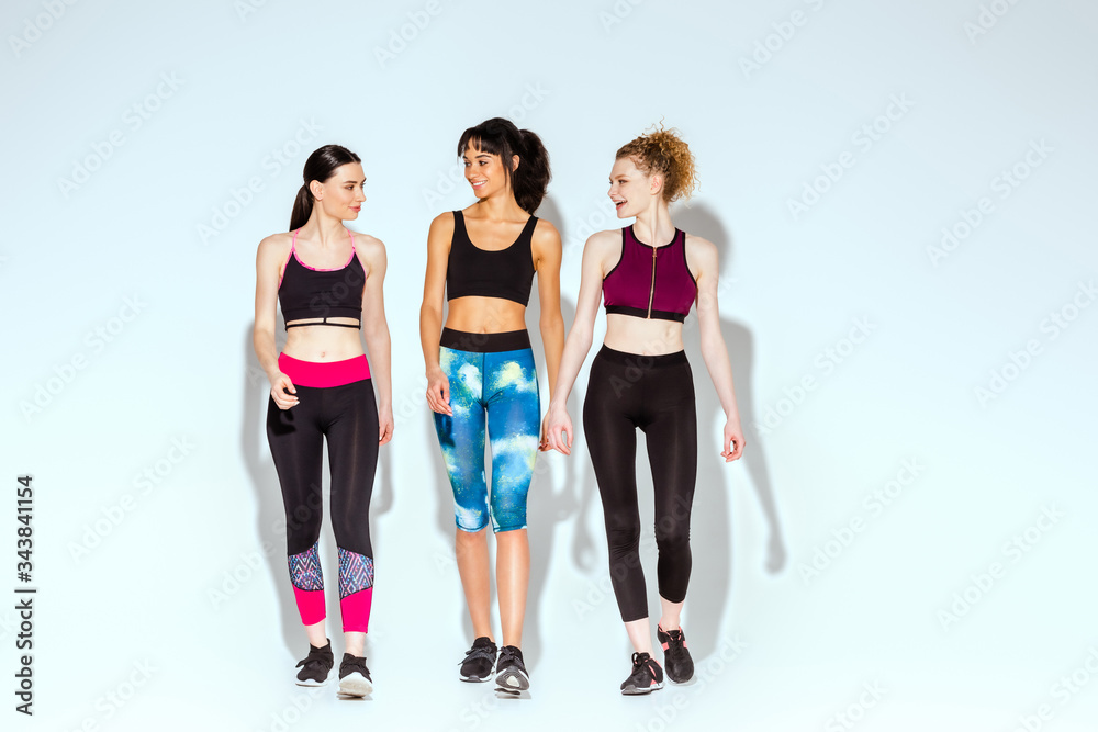 Fototapeta premium multicultural and sportive women walking on white