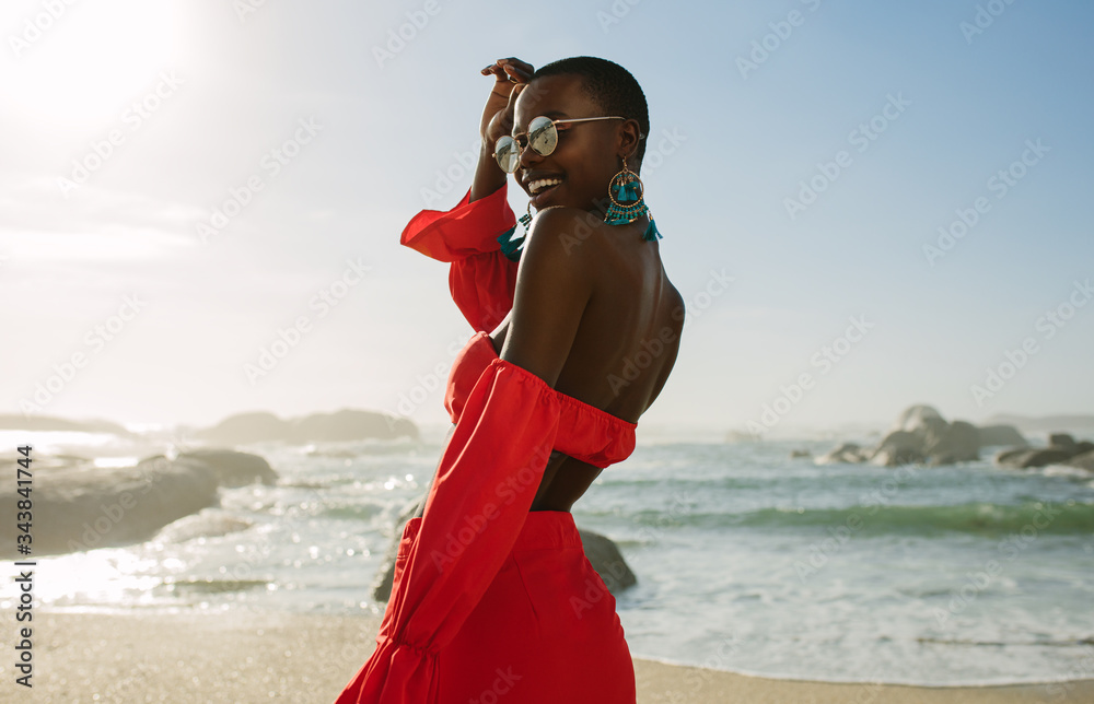 Beautiful african woman in red dress enjoying on the beach - obrazy, fototapety, plakaty 