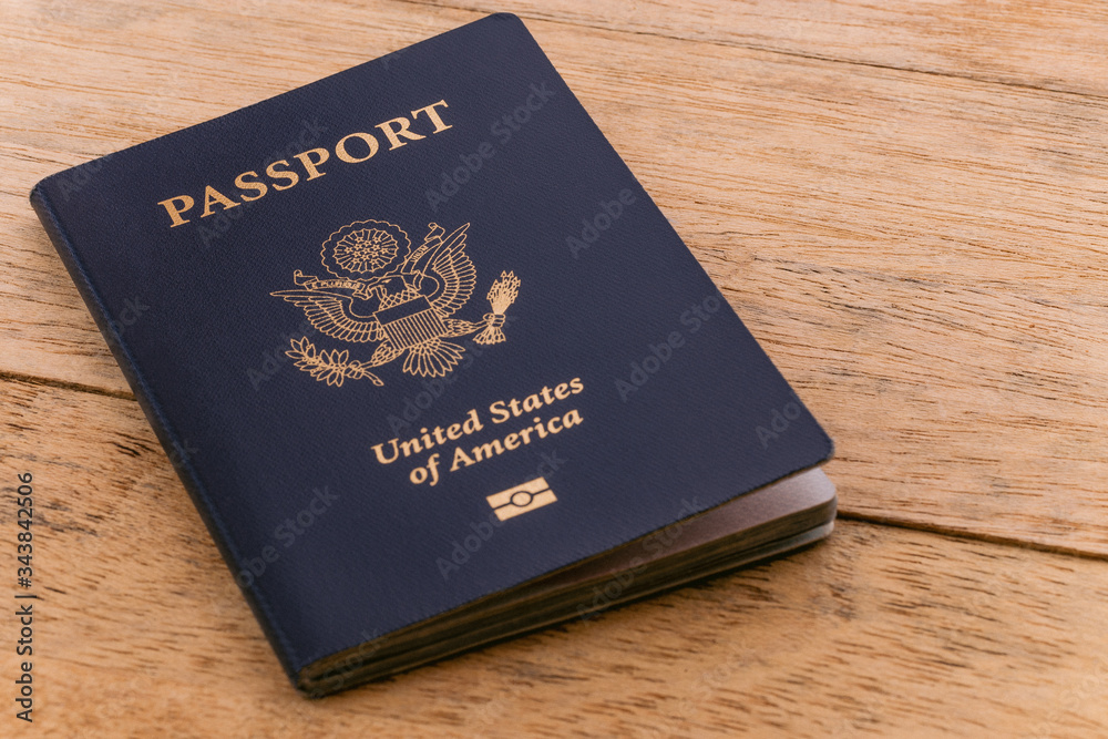 A blue American passport sitting on a wooden table A blue American passport sitting on a wooden table