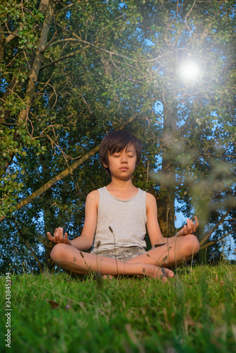 Young Asian boy practicing yoga outdoors