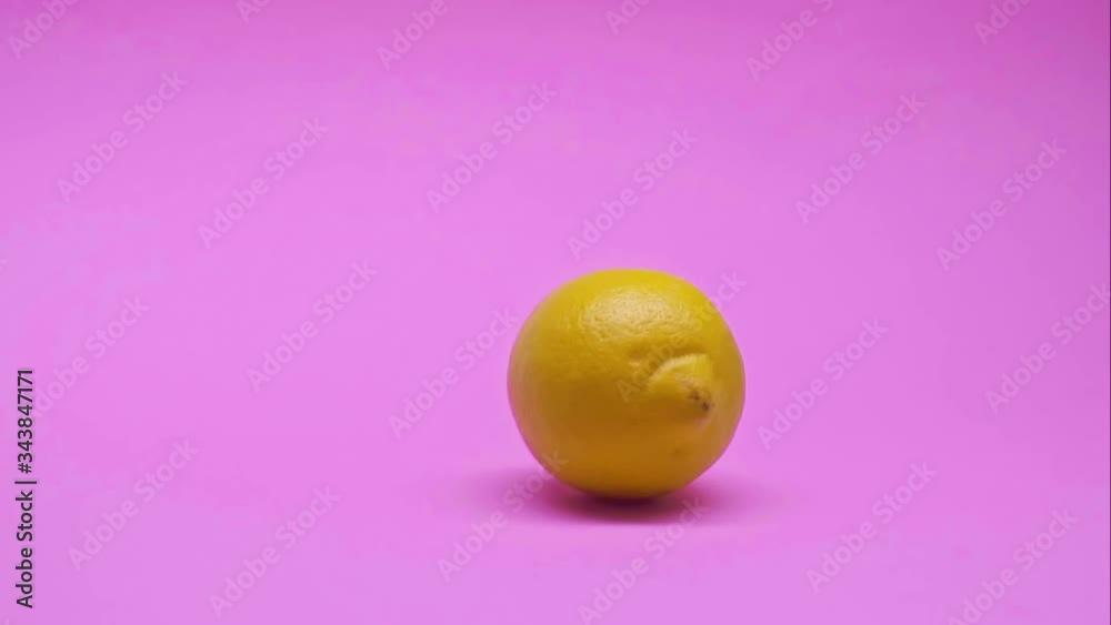 Lemon rolls over a pink background. Healthy lifestyle and vegetarian concept. Slow motion. Lemon rolls over a pink background. Healthy lifestyle and vegetarian concept. Slow motion.