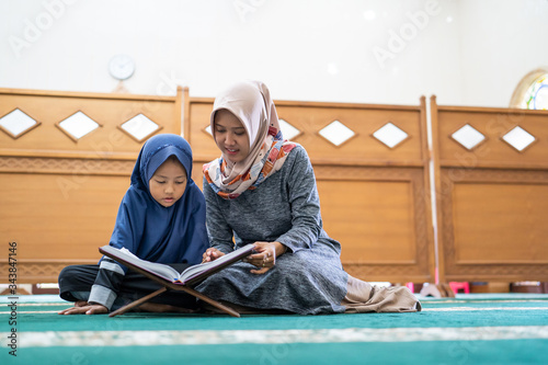 kid learning to read quran with muslim teacher or ustad photo