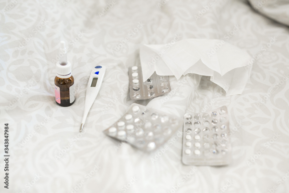 medicines with a thermometer lying on the bed medicines with a thermometer lying on the bed
