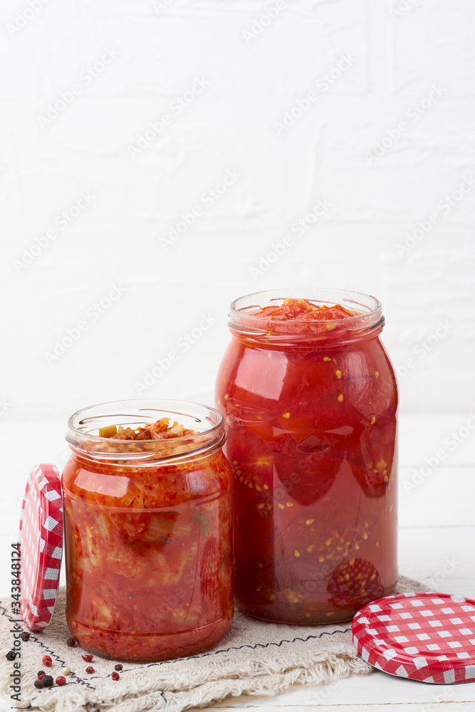 Fermented Chinese cabbage, tomatoes in a jar on a white background. Kimchi. Korean food. Copy space. Fermented and vegetarian preserved food concept. Fermented Chinese cabbage, tomatoes in a jar on a white background. Kimchi. Korean food. Copy space. Fermented and vegetarian preserved food concept.