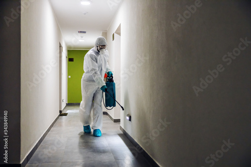 Worker in sterile suit and mask sterilizing hall of a building from corona virus / covid 19. © dusanpetkovic1