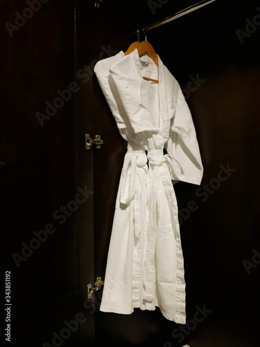 2 White bathing gowns hang in wooden wardrobe