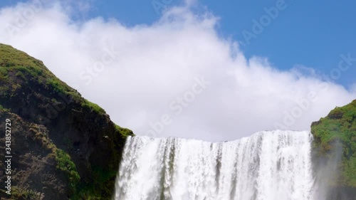 Iceland waterfall Skogafoss in Icelandic nature landscape. Famous tourist attractions and landmarks destination in Icelandic nature landscape on South Iceland. Wide view zoom of a waterfall in Iceland