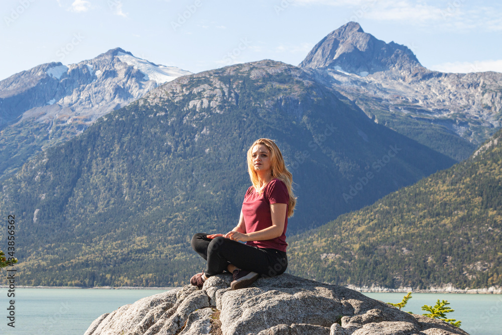Young woman in the mountains. Girl meditating outdoors.