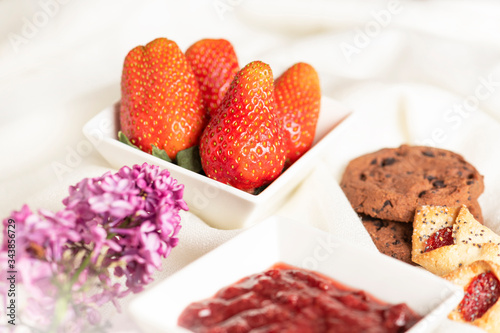 Morning breakfast. Fresh strawberry, strawberry jam and cookies on the white background.