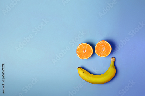 Smiley face with two oranges and a banana with copy space on a blue background