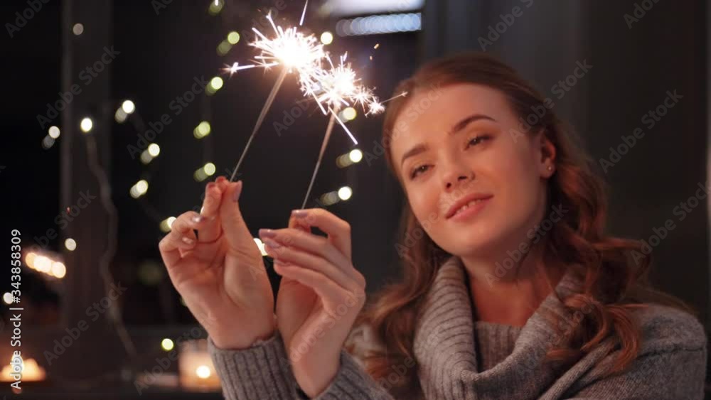 christmas, holiday and people concept - happy young woman with sparklers at home at night christmas, holiday and people concept - happy young woman with sparklers at home at night