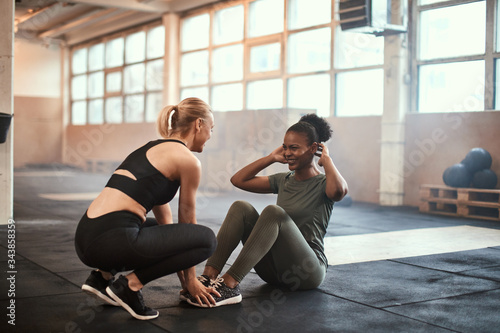 Young woman laughing while doing sit-ups with a friend