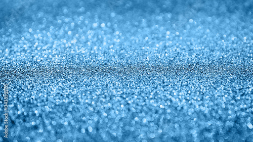 Classic blue abstract background with shiny glitter. Blue festive sparkling macro texture. Holiday backdrop with copy space.