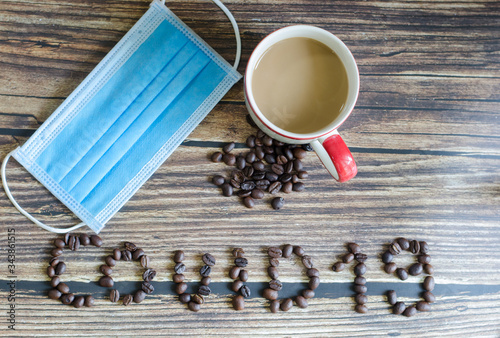 Hot coffee cup with and mask to stop the Covid-19 virus. on the wooden table background