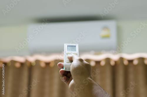 Close up hands press the remote control with air conditioner, energy-saving concept