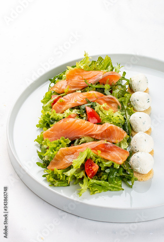 Salmon salad with cheese balls on a white plate