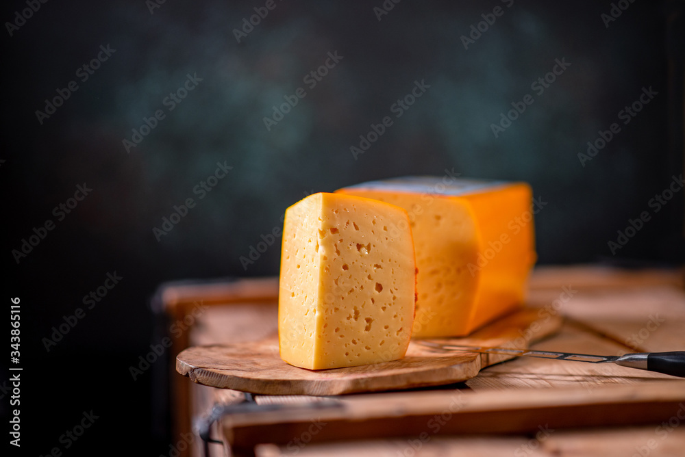 Fototapeta premium Medium hard cheese gouda edam on wooden board on sunlight table traditional table texture