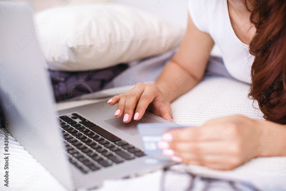 Fototapeta premium Self-isolation at home. woman hands shopping online at home with bank card and laptop.