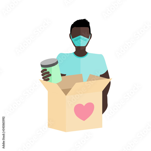 Man wearing a mask packing a box full of food items to give to those in need of help during the COVID-19 coronavirus pandemic
