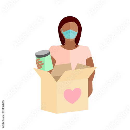 Woman wearing a mask packing a box full of food items to give to those in need of help during the COVID-19 coronavirus pandemic