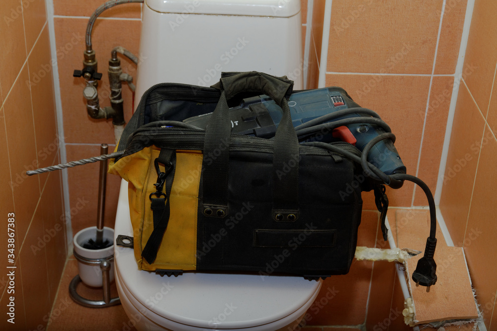 tool bag on the toilet. opening the lining of the toilet, replacing pipes.