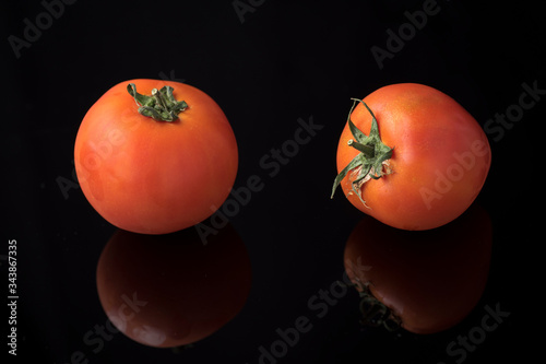 ripe red tomatoes on a shiny methacrylate surface